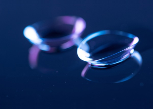 两片隐形眼镜放在深蓝色反光表面上的特写镜头